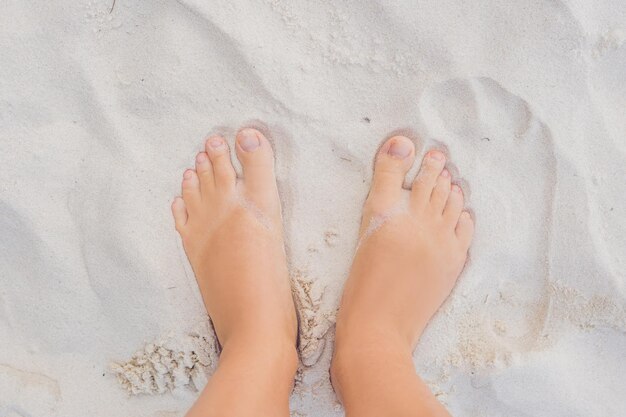 Pernas femininas na praia na areia branca