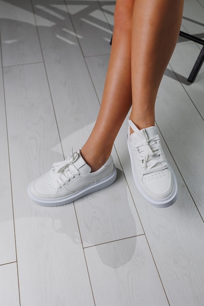Pernas femininas perfeitas em tênis clássicos brancos Pernas femininas lindas em sapatos de verão em sapatos brancos