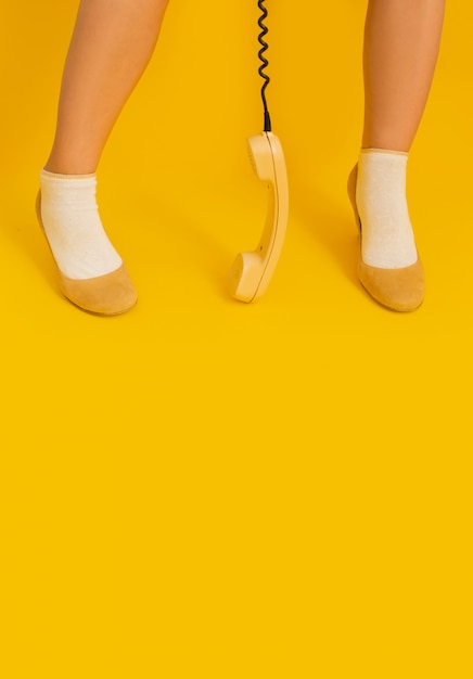 Pernas fundo amarelo retrô aparelho receptor tubo sapatos Lady vintage telefone 80s 90s