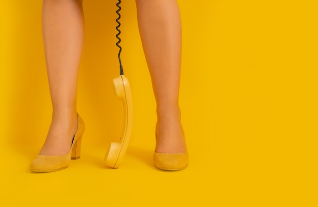 Pernas fundo amarelo retrô aparelho receptor tubo sapatos Lady vintage telefone 80s 90s