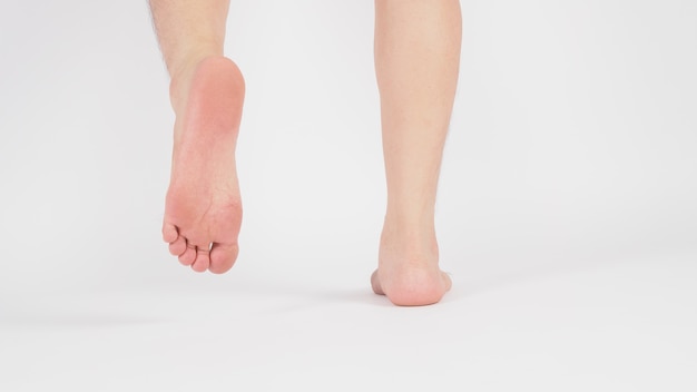 Pernas masculinas asiáticas com os pés descalços isolados no fundo branco