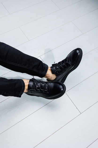 Pernas masculinas em jeans preto closeup em tênis casuais de couro preto Sapatos masculinos confortáveis de meia estação