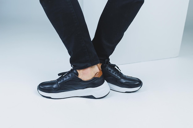 Pernas masculinas em sapatos casuais de cor preta, feitos de couro genuíno, homens em sapatos em tênis pretos Foto de alta qualidade