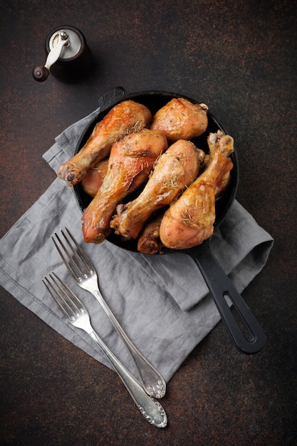 Pernas pontudas de frango frito em uma frigideira de ferro fundido em um fundo escuro de concreto ou pedra