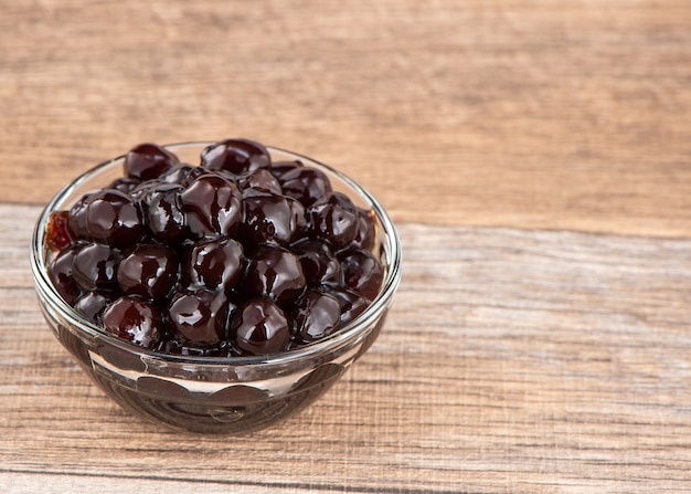 Foto pérola de tapioca, cobertura de bolha para chá ou outra bebida, em uma xícara, coloque sobre a mesa de madeira. copie o espaço