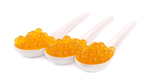 Pérolas de tapioca amarelas para chá bolha isoladas no fundo branco. Pérolas de tapioca em colher de cerâmica.