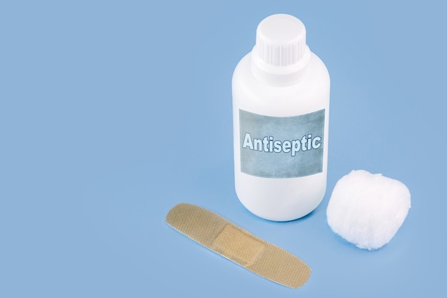 Peróxido de hidrogênio, em embalagem plástica branca, com band-aid e superfície azul isolada, medicamento anti-séptico