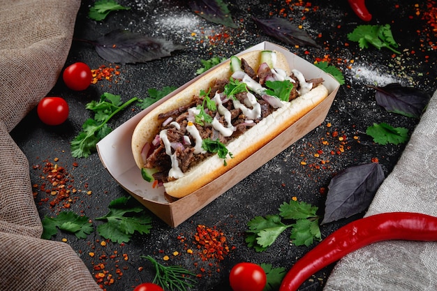 Perrito caliente con relleno de verduras con carne de pollo y hierbas en una mesa de piedra oscura El concepto de comida rápida y restaurantes de entrega