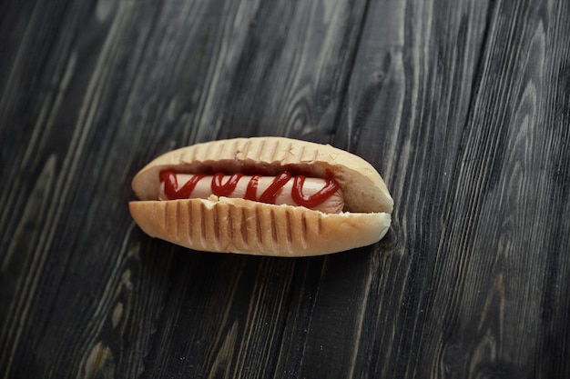 Perrito caliente con salsa de tomate en la foto de fondo de madera oscura con co