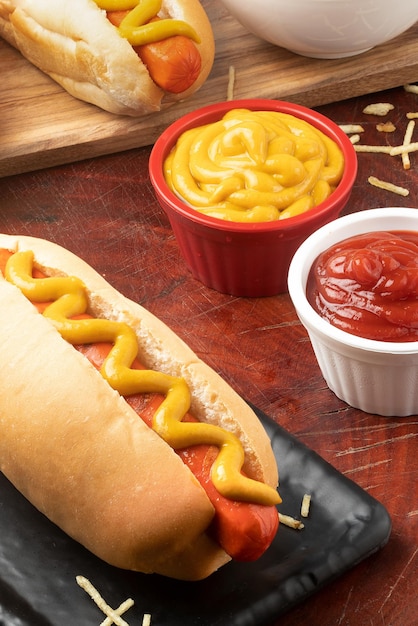 Perrito caliente servido con ketchup de mostaza y palitos de patatas