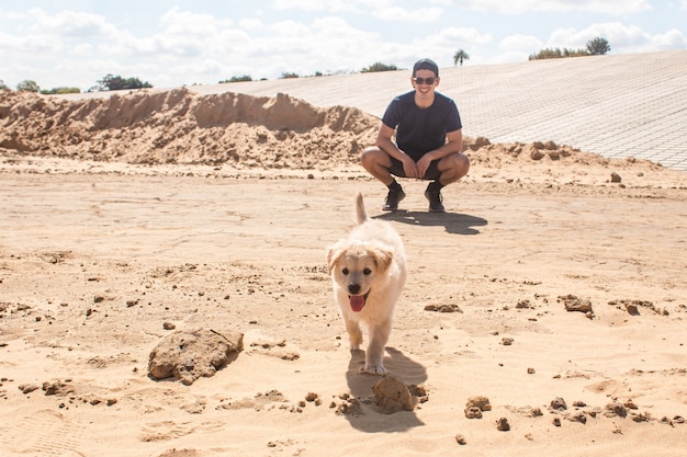 Perrito paseando por la arena con su dueño.