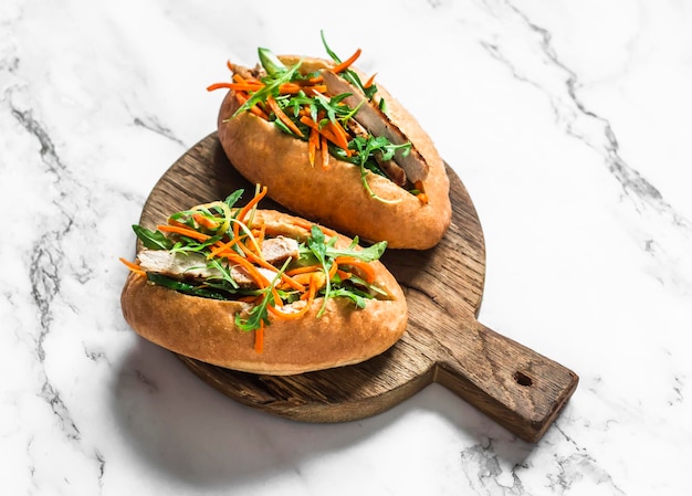 Perritos calientes Banh Mi de cerdo en una tabla de cortar en una vista superior de fondo claro