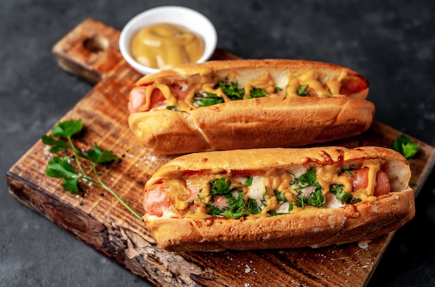 Perritos calientes franceses al horno con queso y mostaza sobre un fondo de piedra