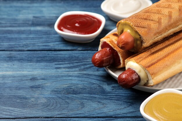 Perritos calientes franceses. Sabrosos perritos calientes en el tablero y salsa en una mesa de madera azul. comida callejera de comida rápida. salchichas en un bollo.