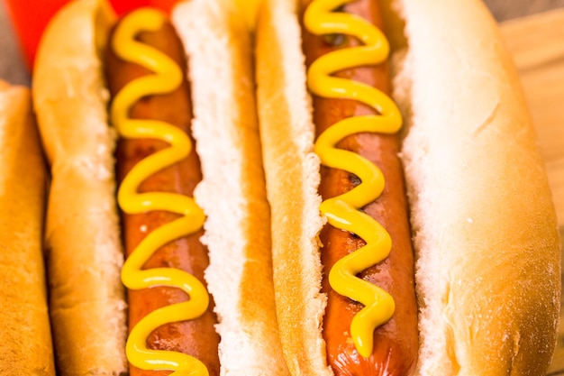 Foto perritos calientes a la parrilla en un pan de hot dog blanco con mostaza y salsa de tomate.