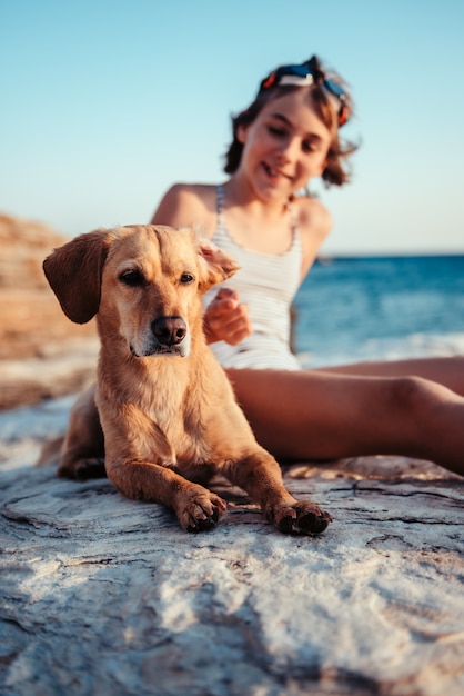 Perro acostado en la playa con una niña