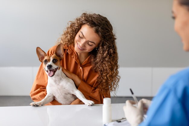 Foto perro alegre con dueña en la oficina de veterinarios compromiso y cuidado