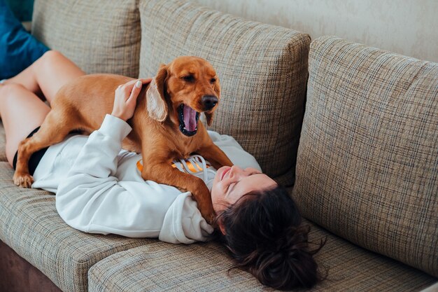 Perro bosteza acostado sobre una niña en casa