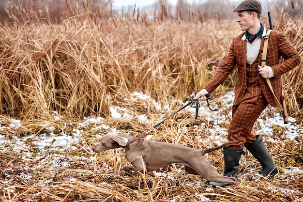 El perro cazador lleva al cazador de hombres a un lado, dirige. en plena naturaleza, lugar rural