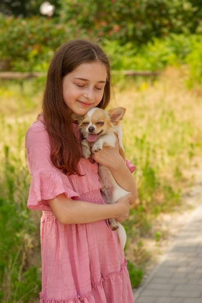 Perro chihuahua en brazos de una niña. Un adolescente con un cachorro.