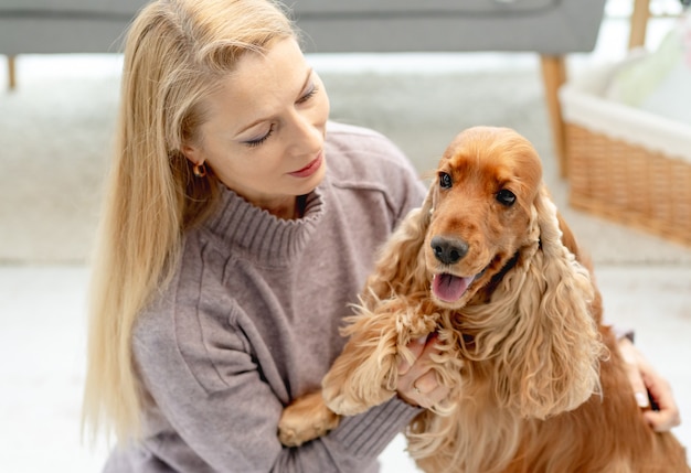 Perro cocker spaniel inglés con amante mujer propietario sentado en el piso en casa