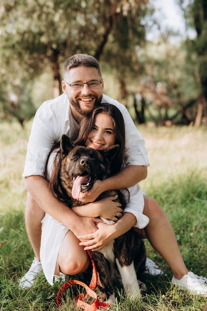 Foto perro grande a pasear con un chico y una chica en la pradera verde