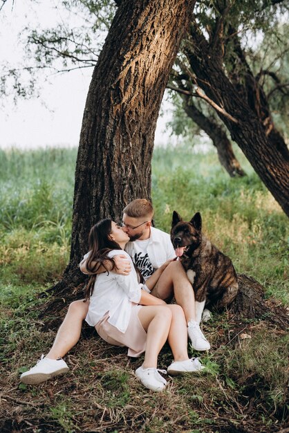 Foto perro grande a pasear con un chico y una chica en la pradera verde