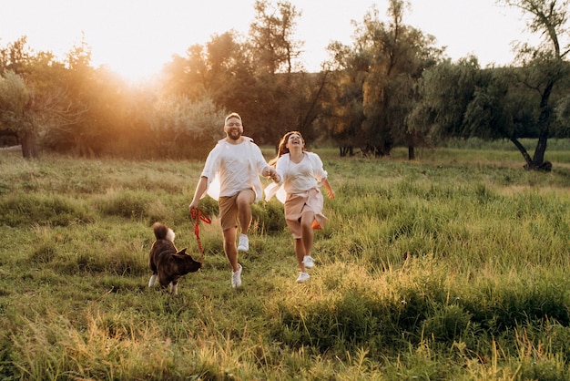 Perro grande a pasear con un chico y una chica en la pradera verde