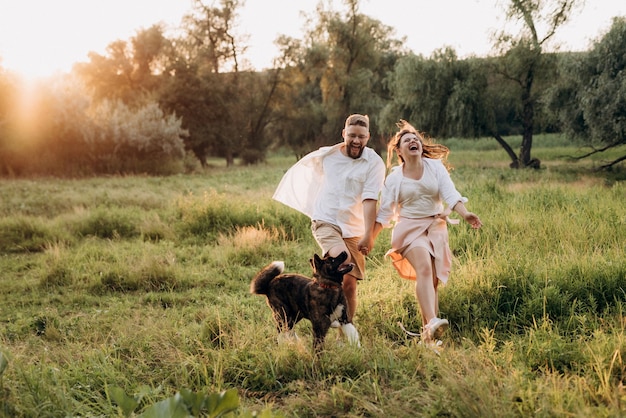 Perro grande a pasear con un chico y una chica en la pradera verde