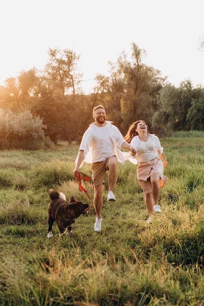 Perro grande a pasear con un chico y una chica en la pradera verde