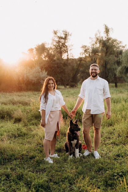 Perro grande a pasear con un chico y una chica en la pradera verde