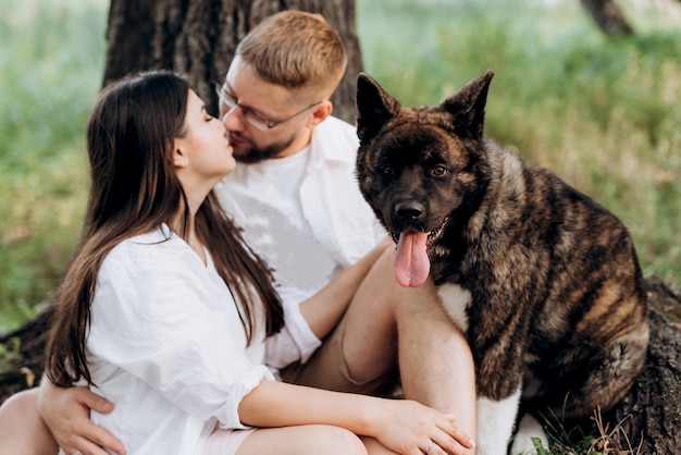 Foto perro grande a pasear con un chico y una chica en la pradera verde