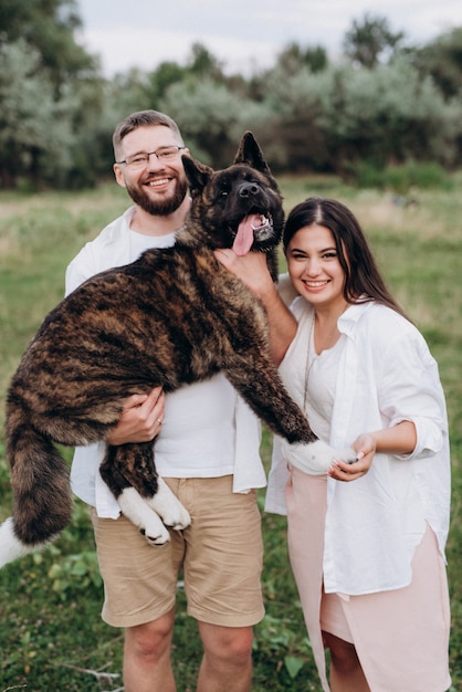 Perro grande a pasear con un chico y una chica en la pradera verde