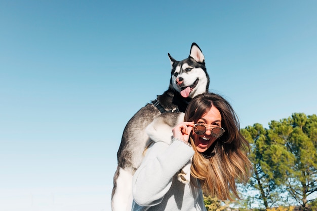 Perro Husky siberiano posando sobre el hombre de la hermosa mujer rubia.