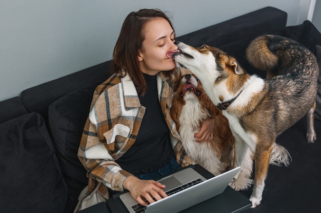 El perro lame a la mujer mientras la niña trabaja en la computadora portátil.