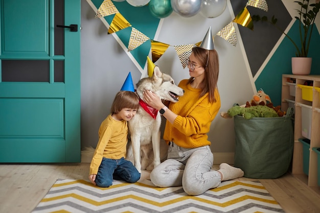 Perro mascota cumpleaños familia madre e hijo abrazan a su perro felicitando feliz cumpleaños