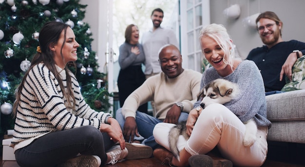 Foto perro de navidad y fiesta con amigos en la sala de estar para celebrar, relajarse y festividad felices fiestas y navidad con mascotas y un grupo de personas en casa para reunirse y celebrar un evento social juntos
