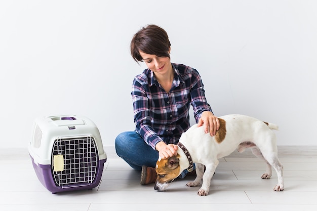 Perro que lleva bolsas y concepto de propietario de mascotas: atractiva mujer alegre en camisa a cuadros tiene favorito