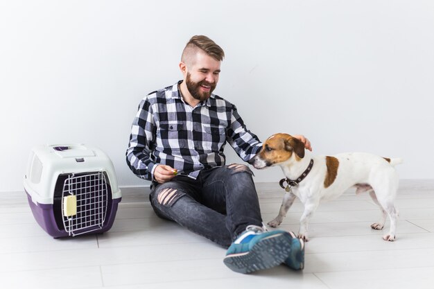 Perro que lleva bolsas y concepto de propietario de mascotas: atractivo macho alegre en camisa a cuadros tiene favorito