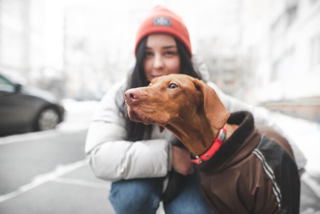 Perro de raza magyar mira hacia un lado, pero la niña sonriente en ropa de abrigo