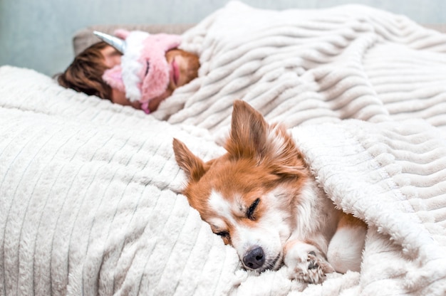 Perro rojo duerme con su dueño en una máscara de dormir rosa en el sofá. Concepto fin de semana y descanso