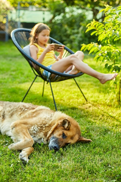 Perro tirado en la hierba lindo niño niña jugando en el teléfono móvil