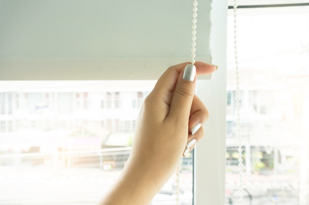 Persiana de cortina de janela por mãos de mulher instalando persianas, closeup.