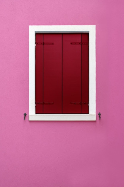 Persiana de madera cerrada sobre fondo rosado