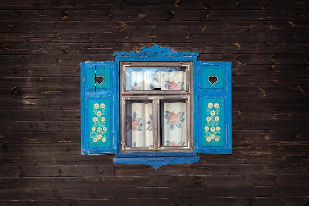 Persianas abertas azuis da velha casa de madeira