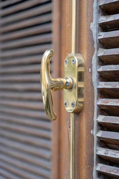 Persianas de madera cerradas y manija de ventana de metal de cerca