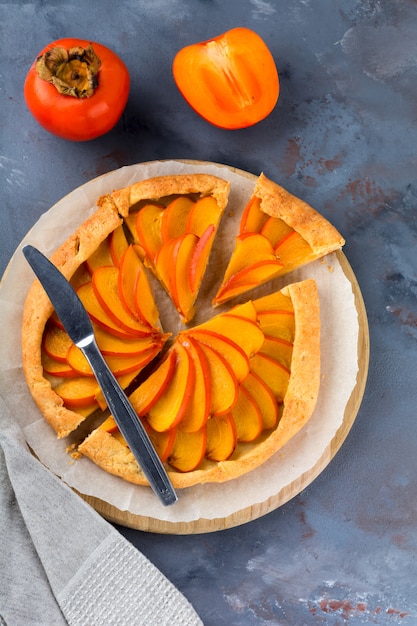 Persimmon Galette, Torte, Torte auf einem grauen Steinhintergrund. Draufsicht. Selektiver Fokus.