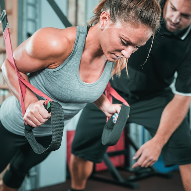 Persönlicher Trainer trainiert auf TRX mit einer Frau im Fitnessstudio