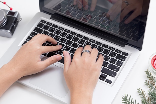 Foto person, die auf dem tisch einen laptop mit weihnachtsdekoration verwendet