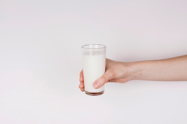 Person, die ein Glas Milch auf weißem Hintergrund hält